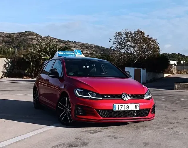 Un Volkswagen Golf rojo está estacionado en un estacionamiento