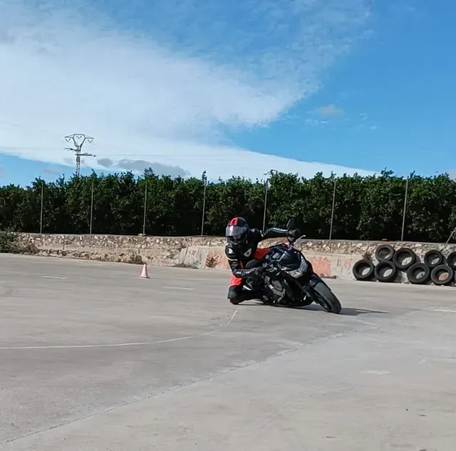 Un hombre conduce una motocicleta en un estacionamiento.
