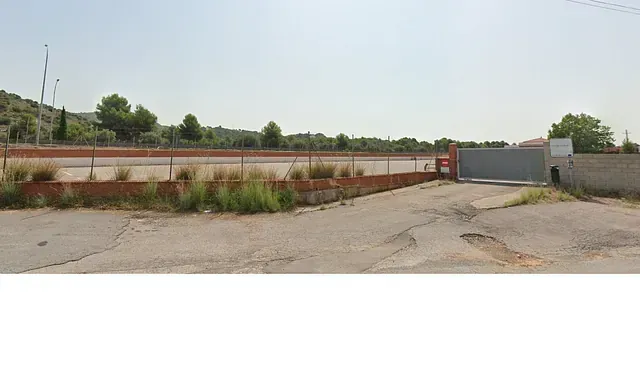 Un gran estacionamiento vacío con una valla y una puerta.