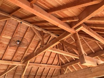 Intérieur industriel abandonné avec poutres apparentes et bois empilé sur un sol poussiéreux