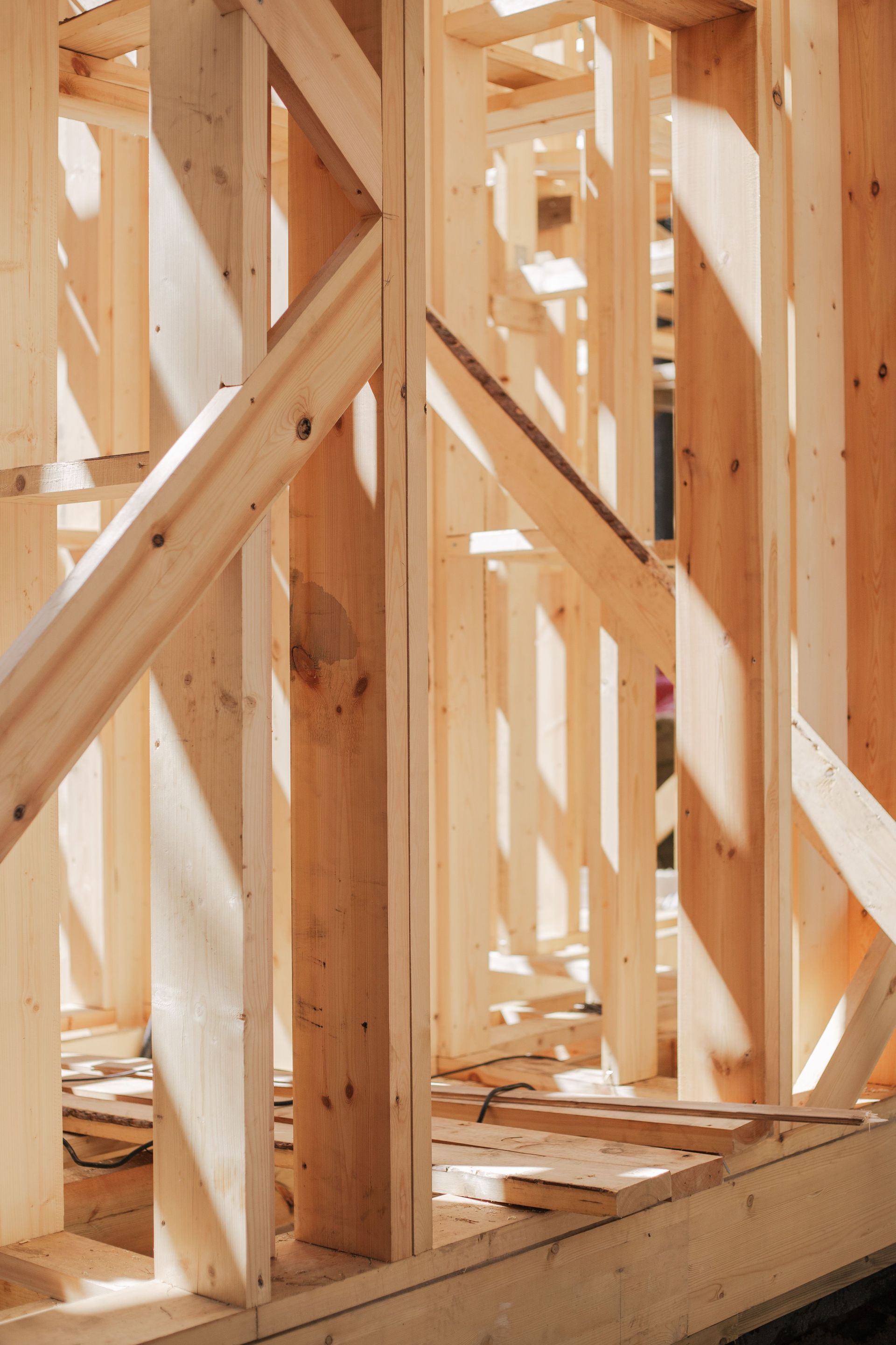 Charpente en bois avec montants verticaux, entretoises diagonales et ombres projetées par la lumière du soleil à l'intérieur de la structure