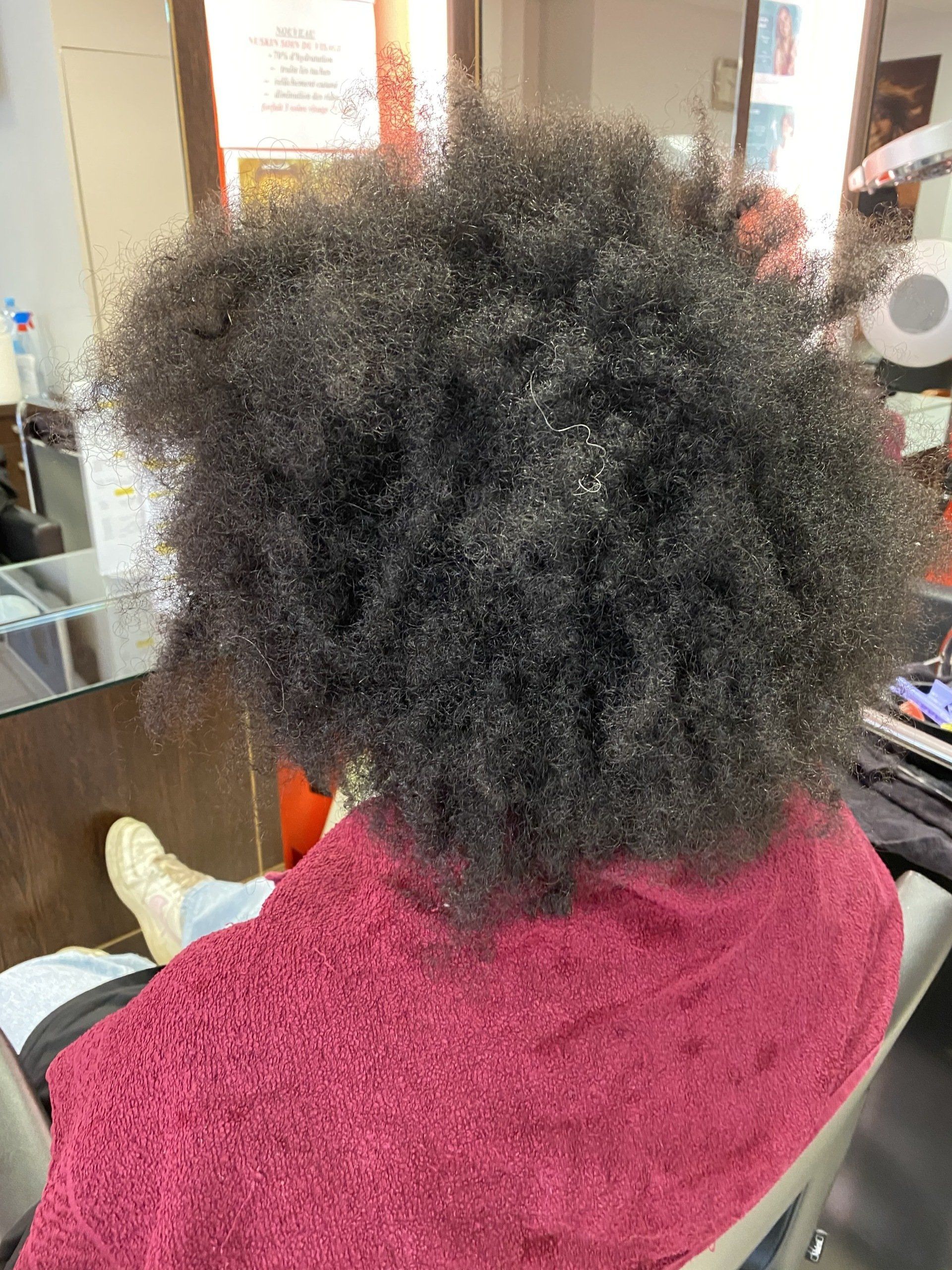 Une femme avec des cheveux très frisés avant un lissage brésilien