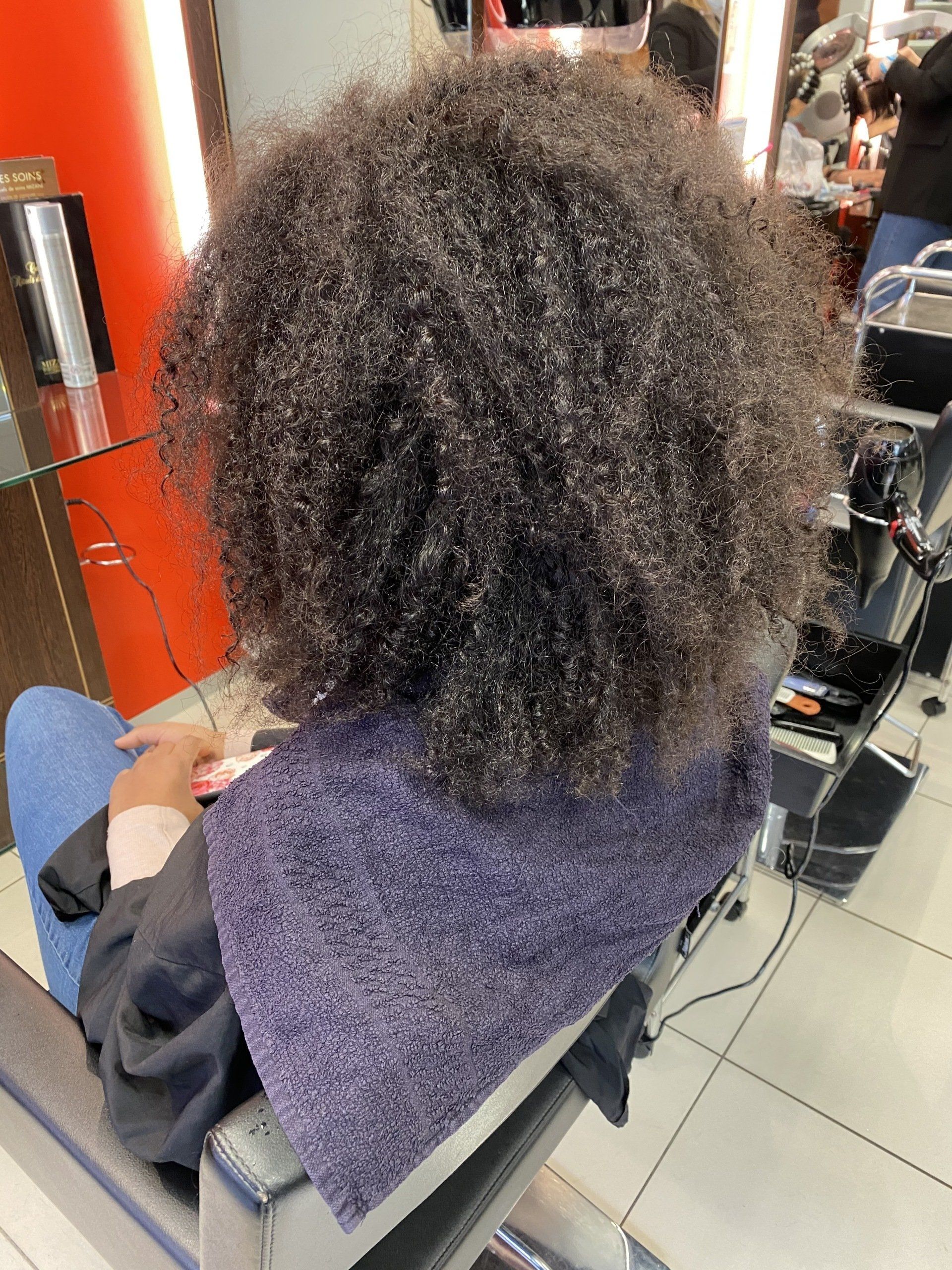 Une cliente avec des cheveux afros qui s'apprête à faire un lissage brésilien