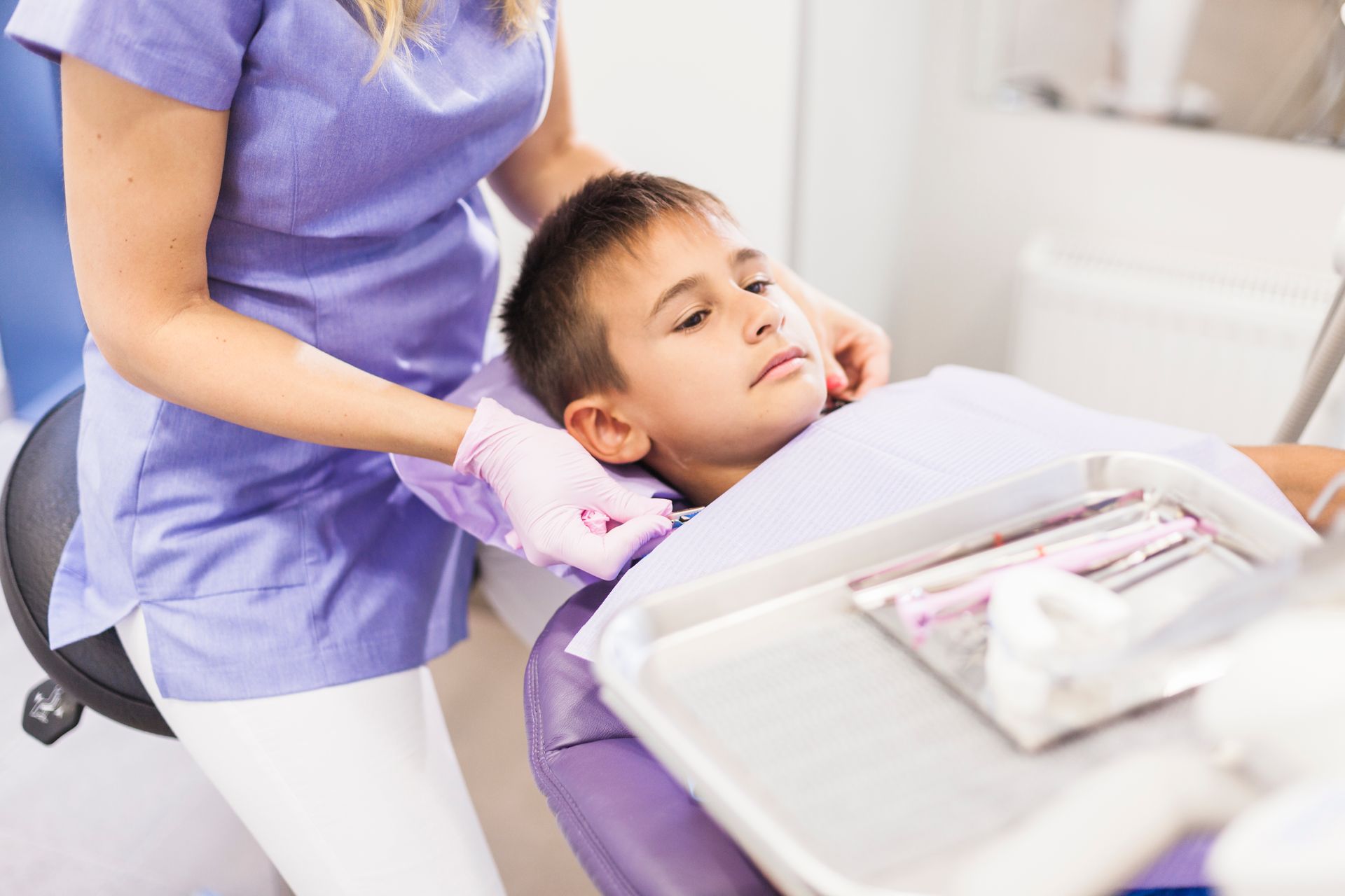 Higienista dental examinando a un niño en el sillón dental durante una revisión.