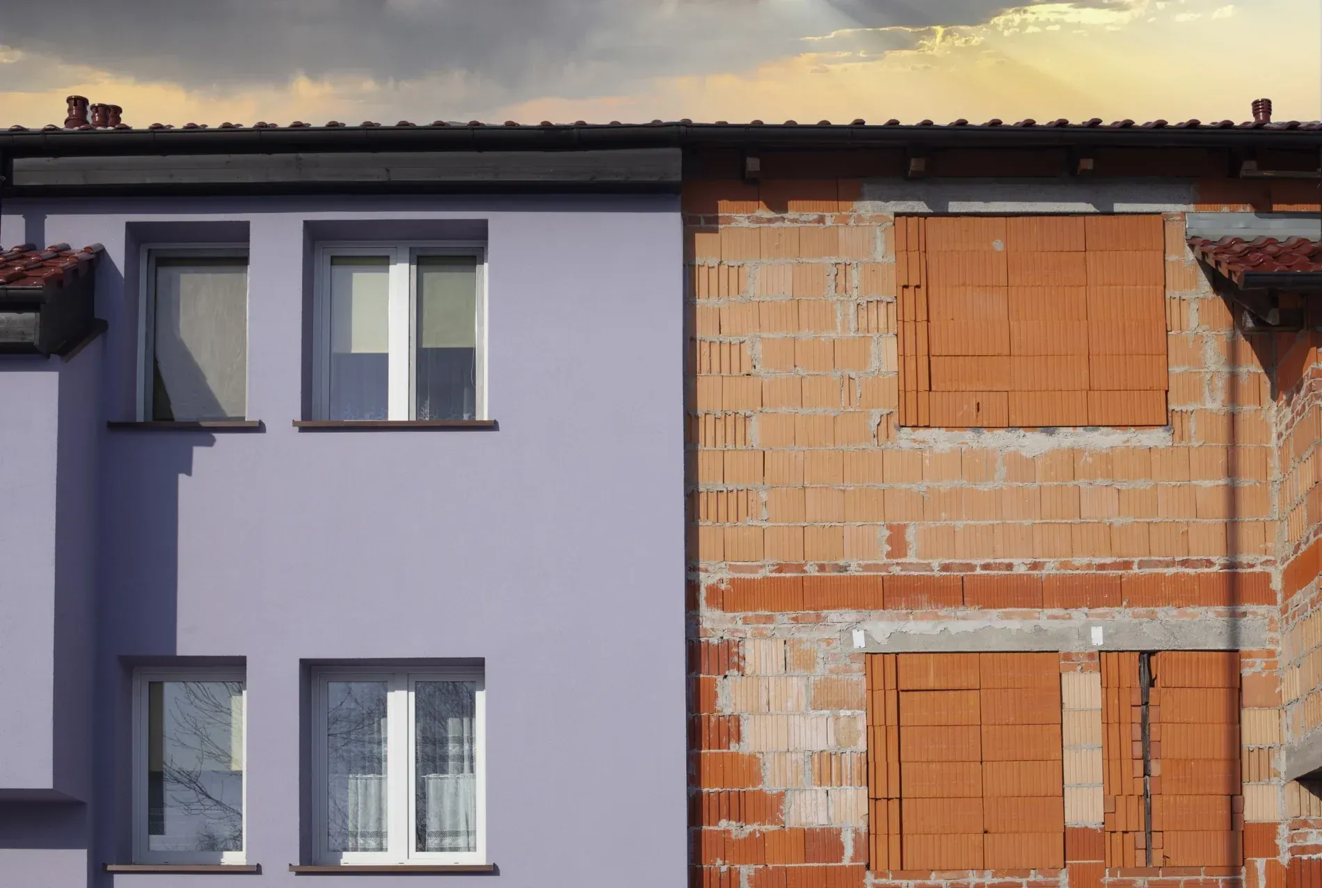 Edificio a medio terminar junto a un edificio terminado con pintura lavanda, contrastando construcción y terminación.