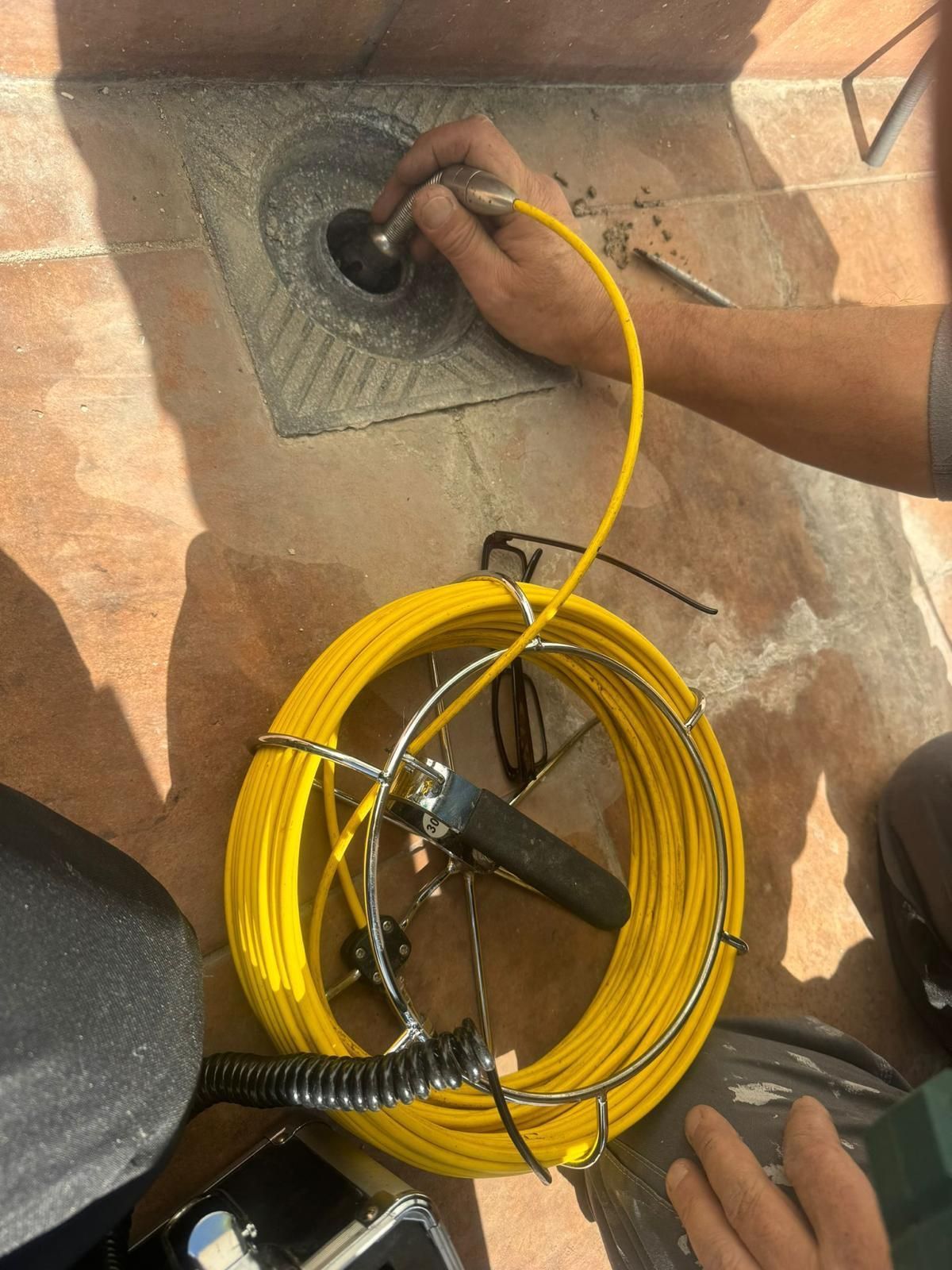 Una persona está trabajando en un desagüe con una manguera amarilla.