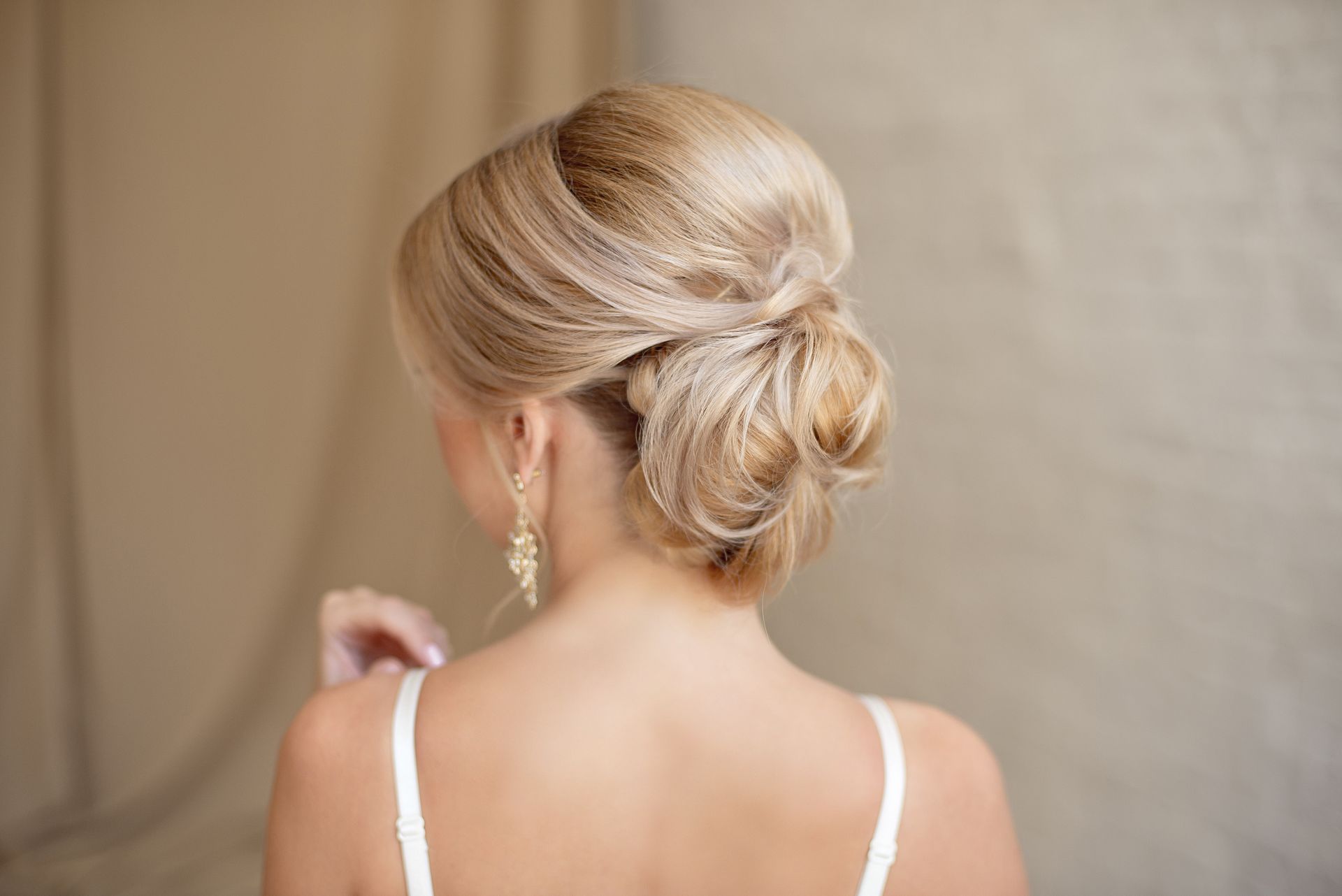 Femme blonde de dos avec un chignon et une robe de  marriage