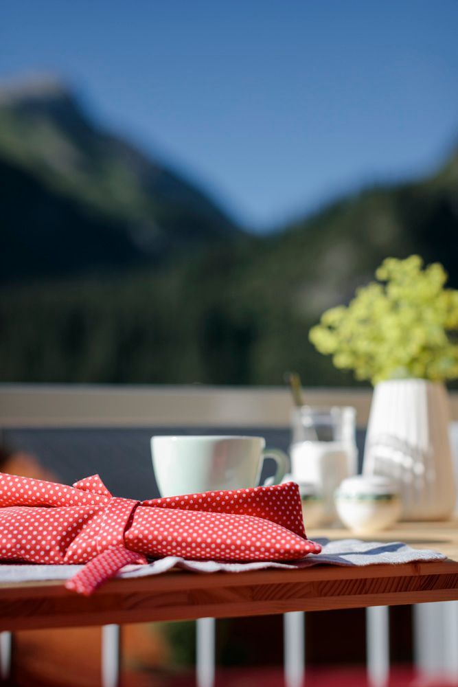 ein Kuchen und eine Tasse Kaffee auf einem Tisch mit Bergen im Hintergrund
