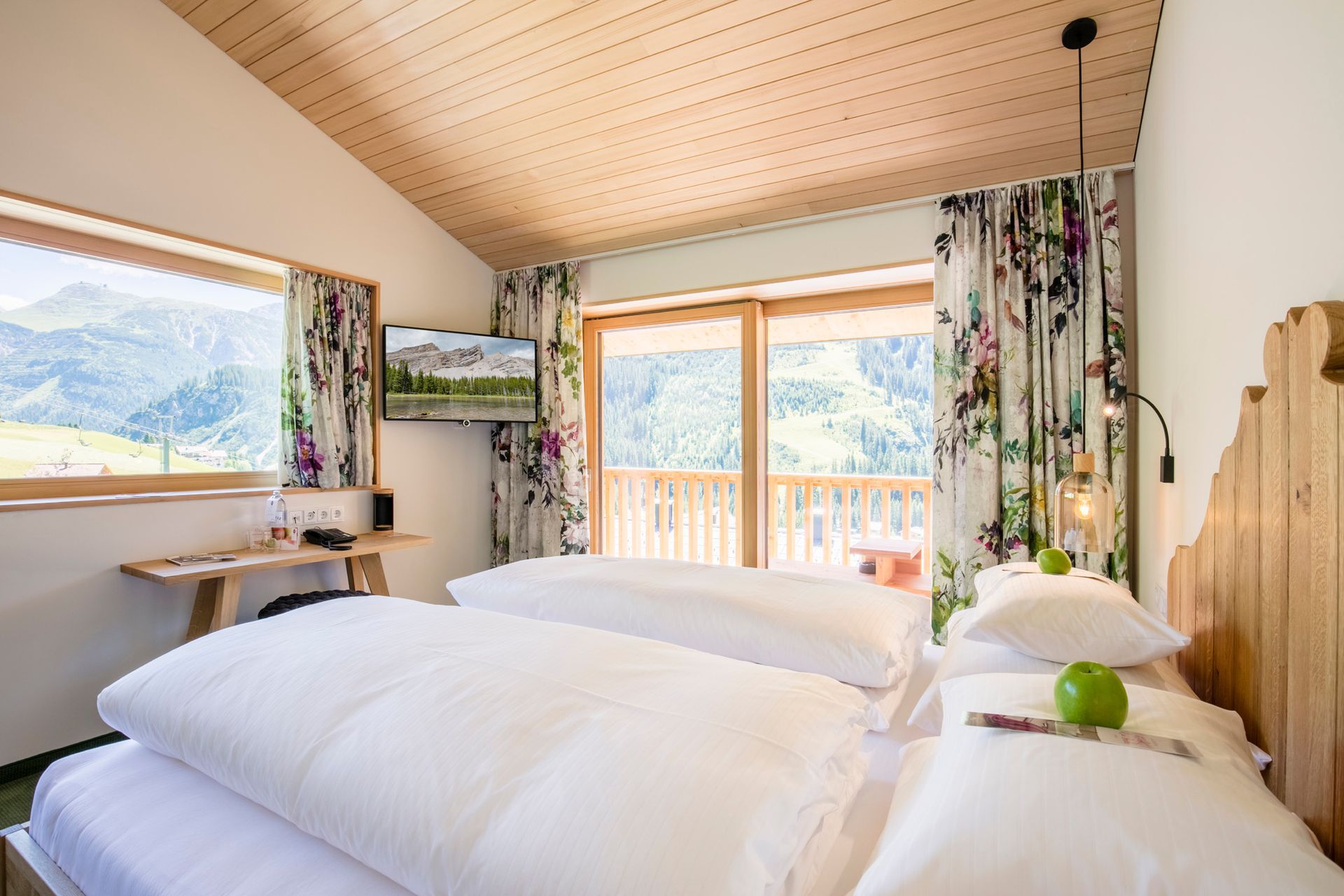 ein Schlafzimmer mit Doppelbett und großen Fenstern mit Blumenvorhängen