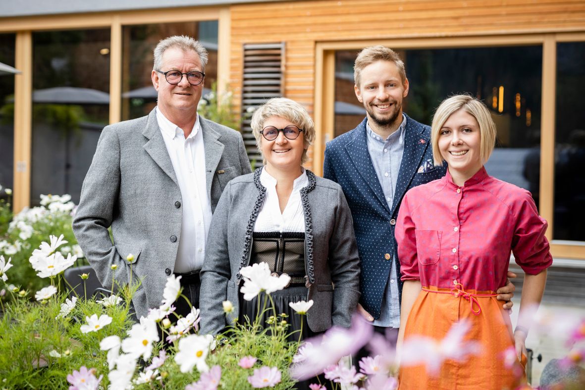 Familie Birk steht vor ihrem Hotel Stäfeli mit Sommerblumen