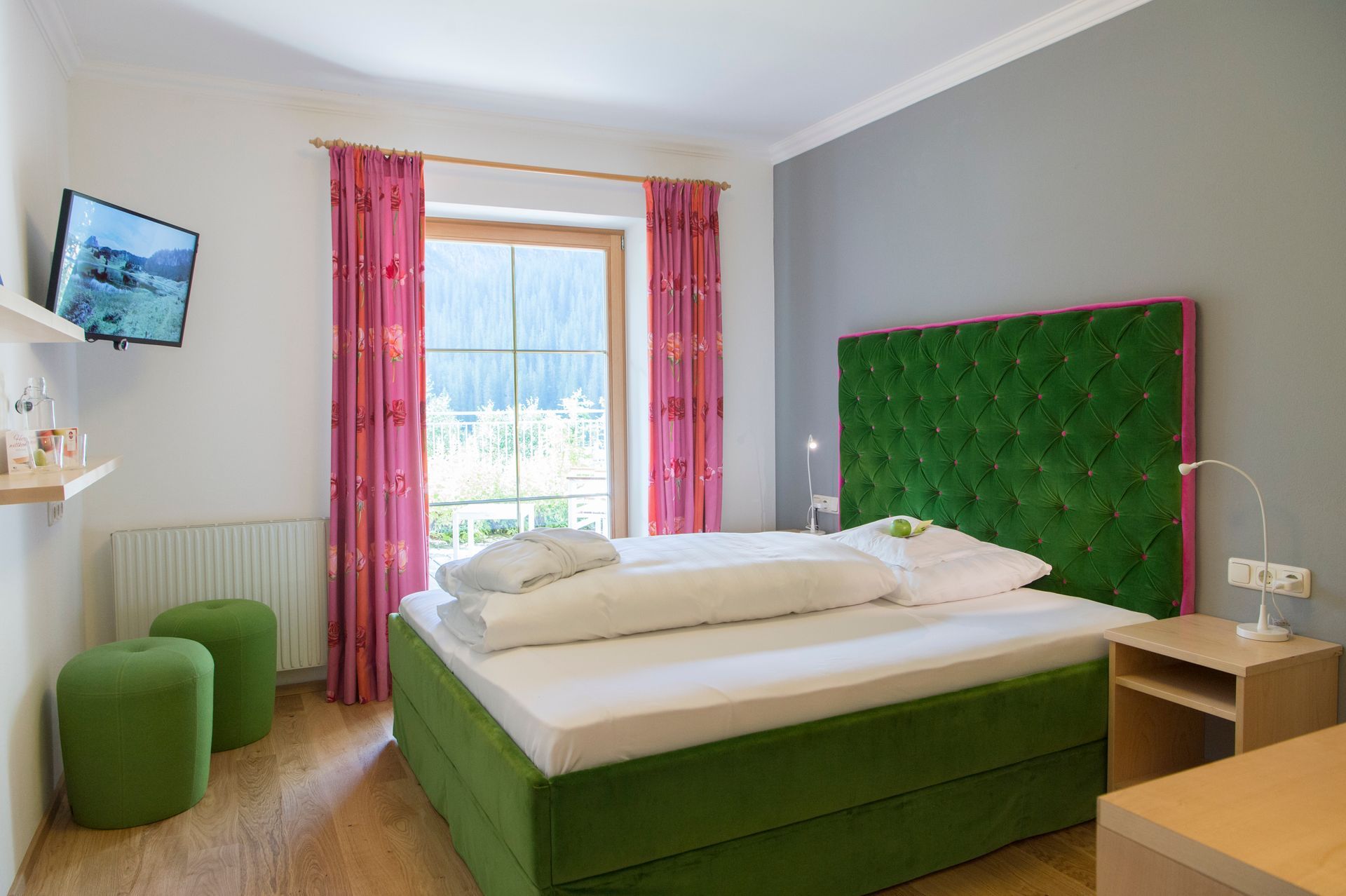 Hotelzimmer mit einem grünen Bett und einem Fernseher .