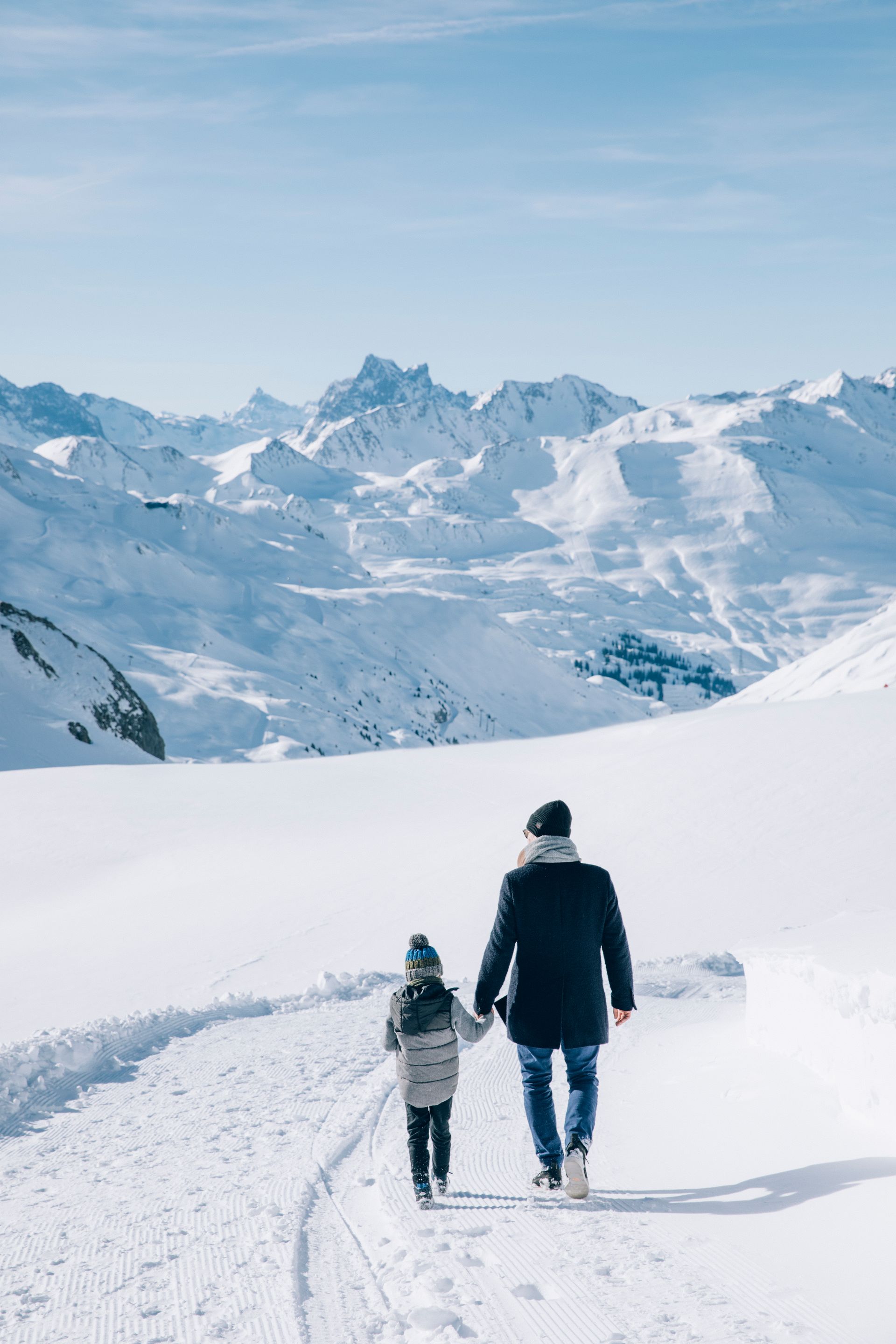 Ein Mann und ein Kind gehen im Schnee spazieren und halten sich an den Händen .