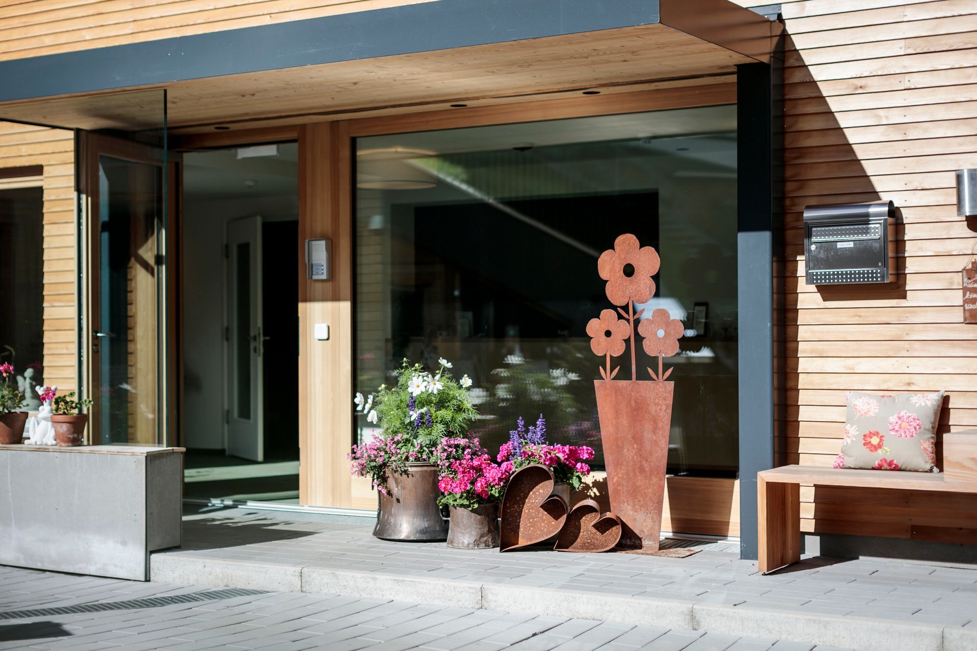 Eine Bank steht vor der Stäeli Holzfassade mit Blumentöpfen davor .