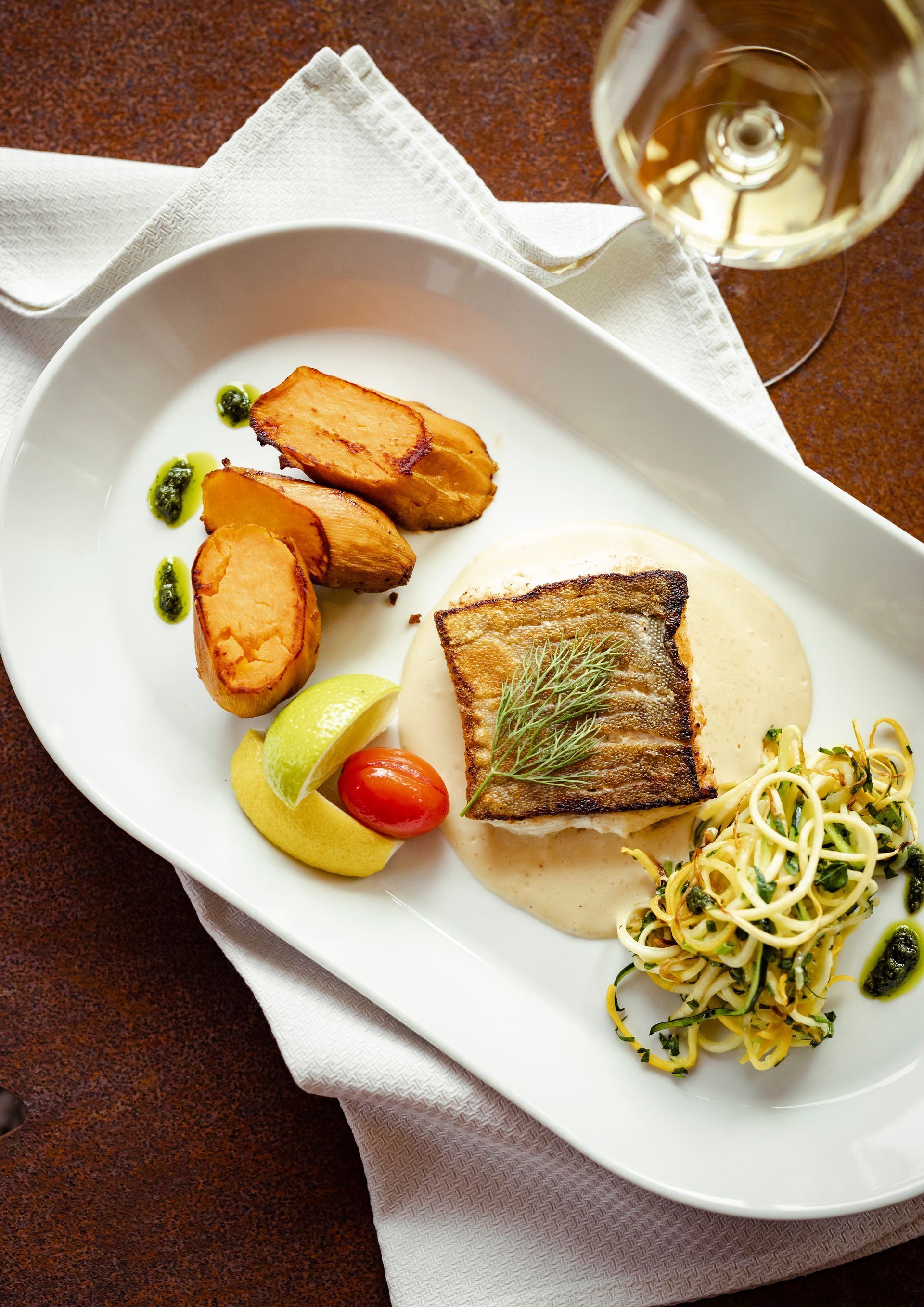 ein weißes Teller mit Essen und einem Glas Wein auf einem Tisch .