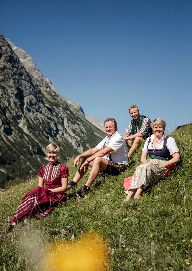Familie Birk sitzt auf der grünen Wiese hinter dem Hotel