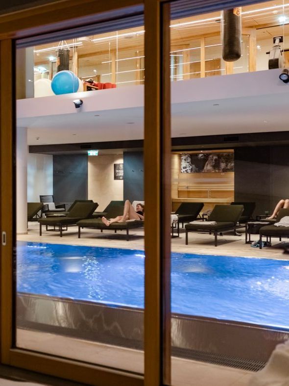 eine Frau liegt auf einem Stuhl neben einem Schwimmbad .