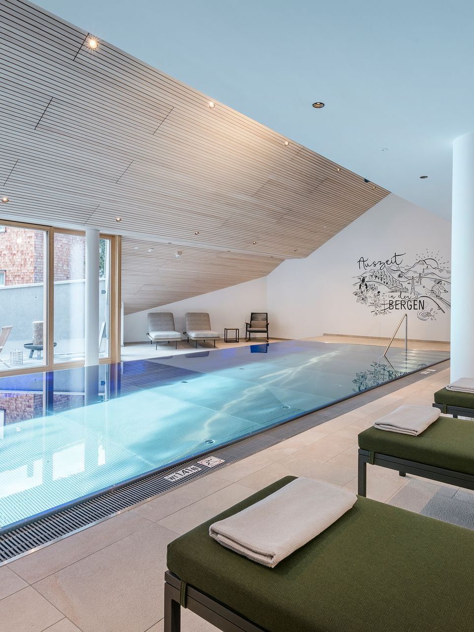 ein großer Swimmingpool mit grünen Liegen