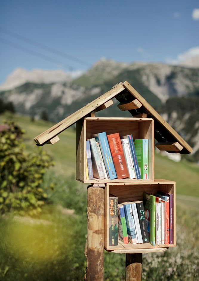 ein Holzhaus mit Büchern darin auf einem Holzpfosten .