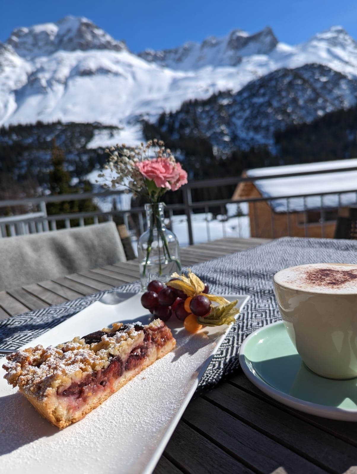 ein Kuchen und eine Tasse Kaffee auf einem Tisch mit Bergen im Hintergrund
