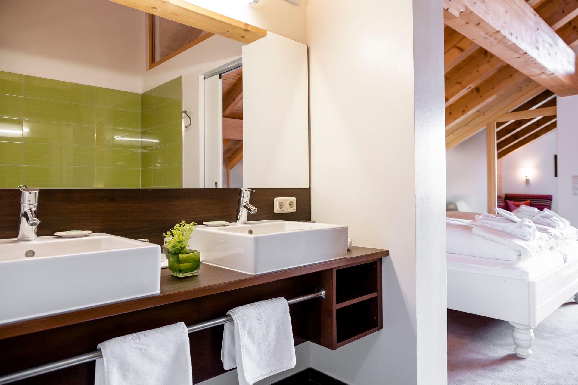 ein Badezimmer mit zwei Waschbecken und einem Spiegel neben einem Bett .
