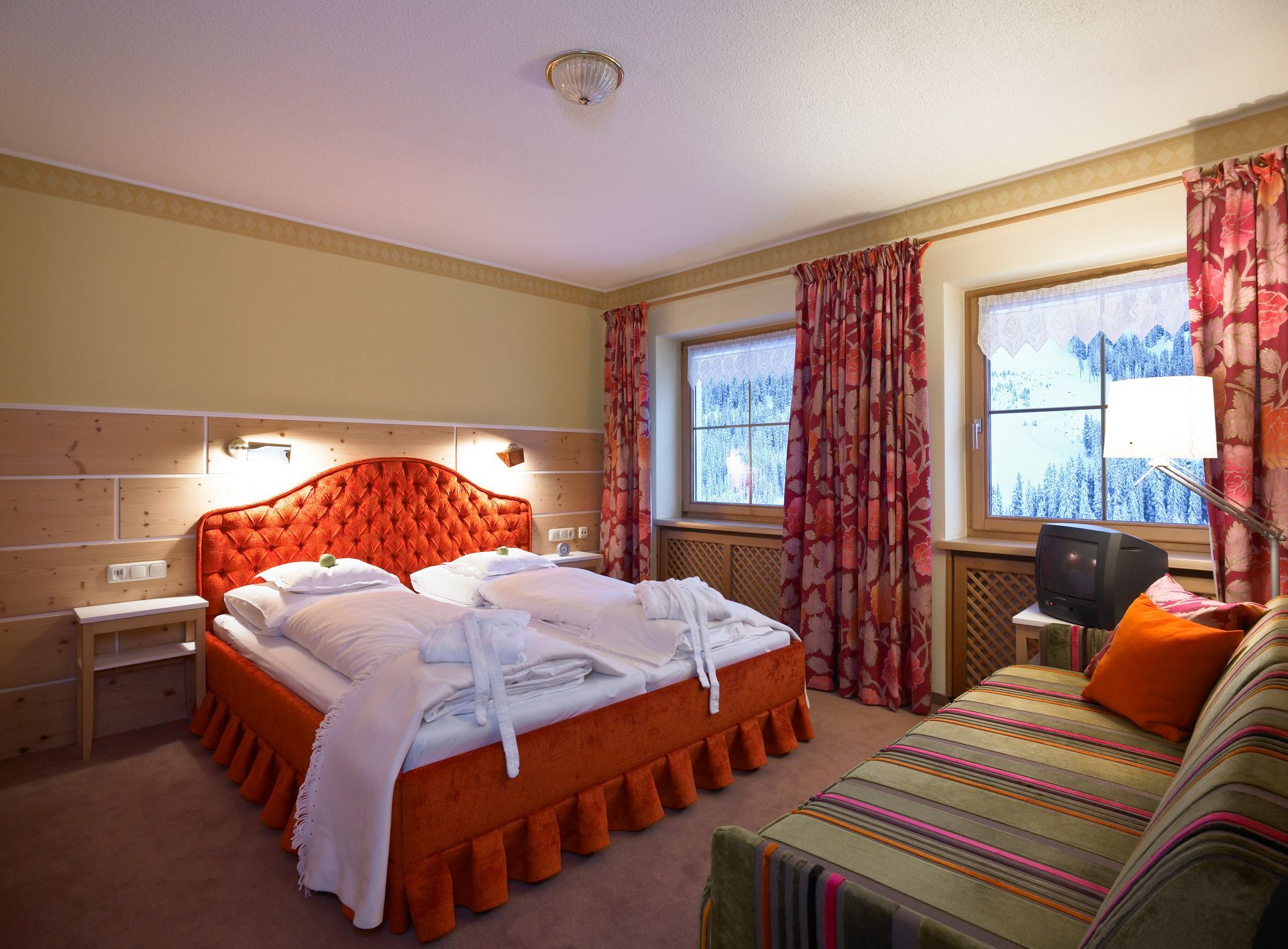 ein Hotelzimmer mit einem großen, roten Bett und einer gestreiften Couch .