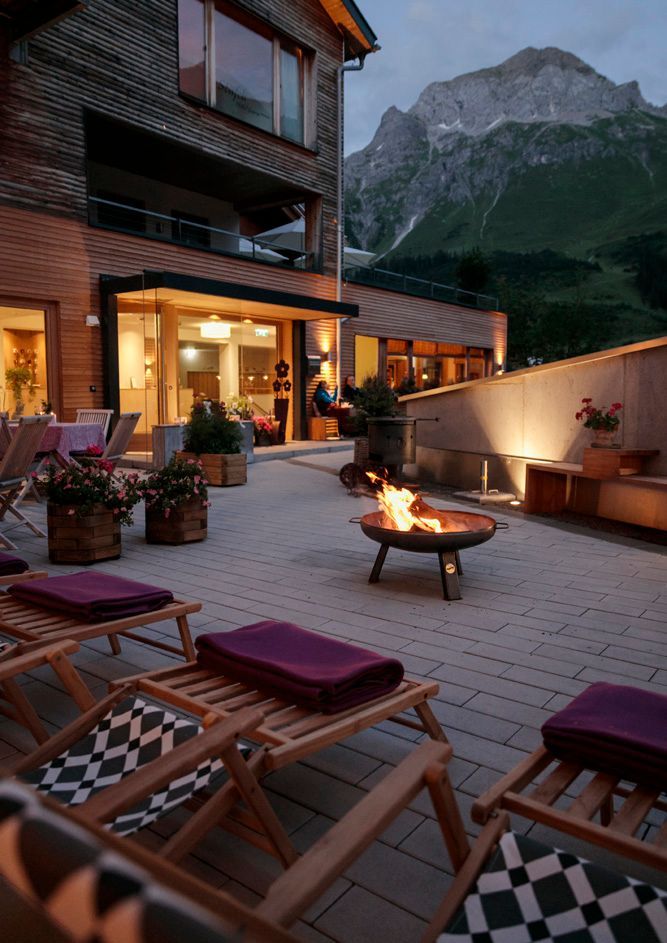 Eine Feuerstelle auf einer Terrasse mit Liegestühlen vor dem Hotel Stäfeli .