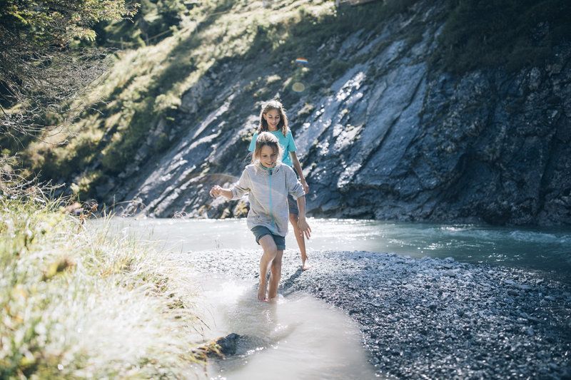 Ein Junge und ein Mädchen laufen barfuß durch einen Fluss .