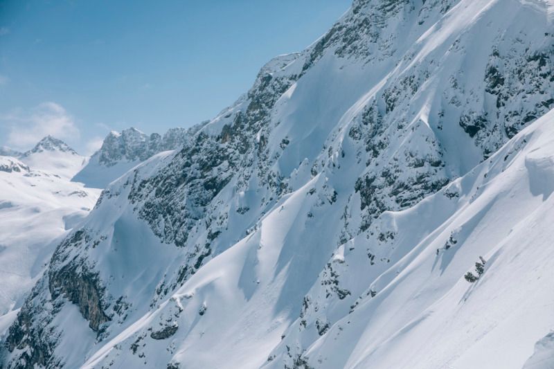 eine schneebedeckte Bergkette mit einem blauen Himmel im Hintergrund .