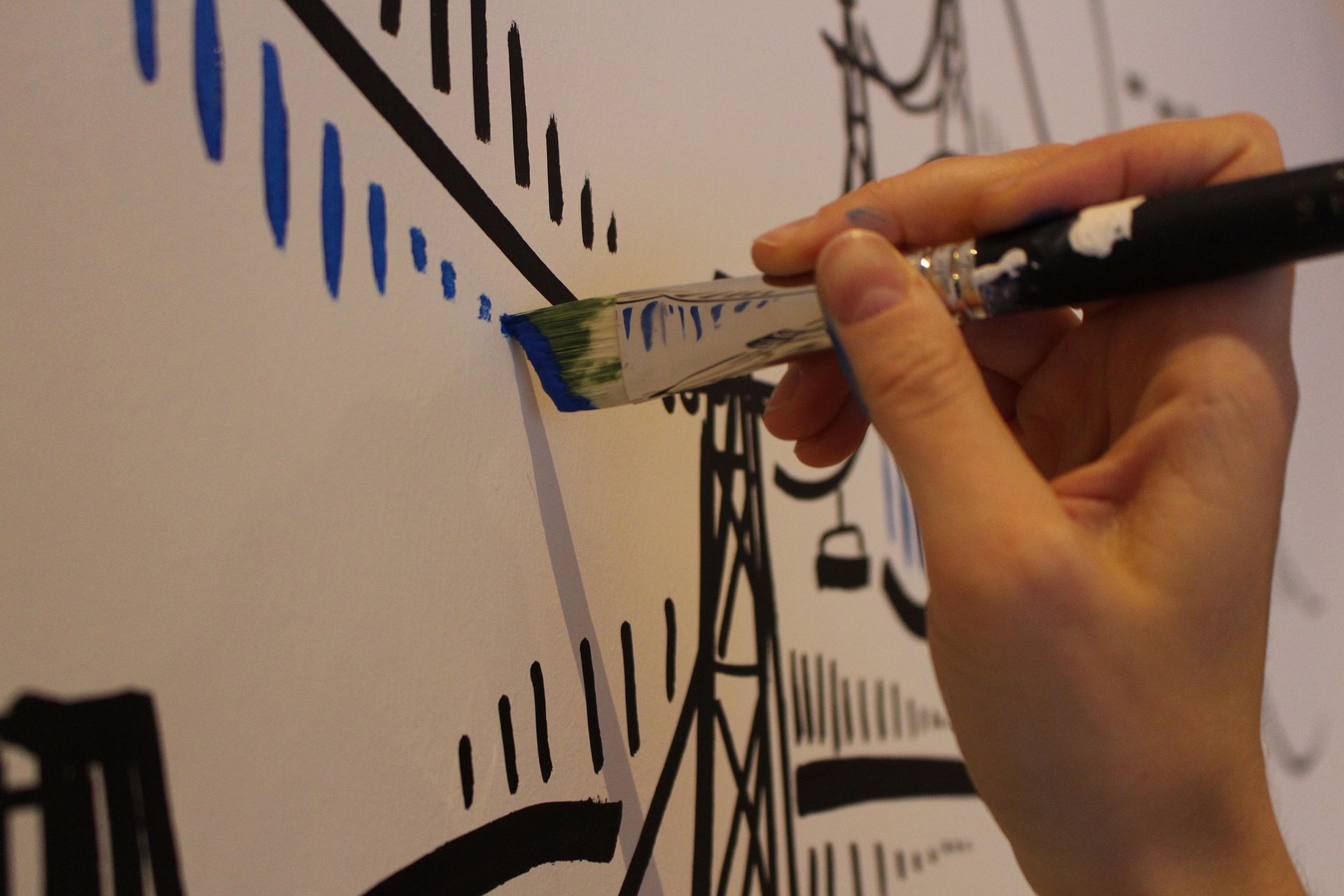 eine Person malt mit einem Pinsel auf einer weißen Wand .