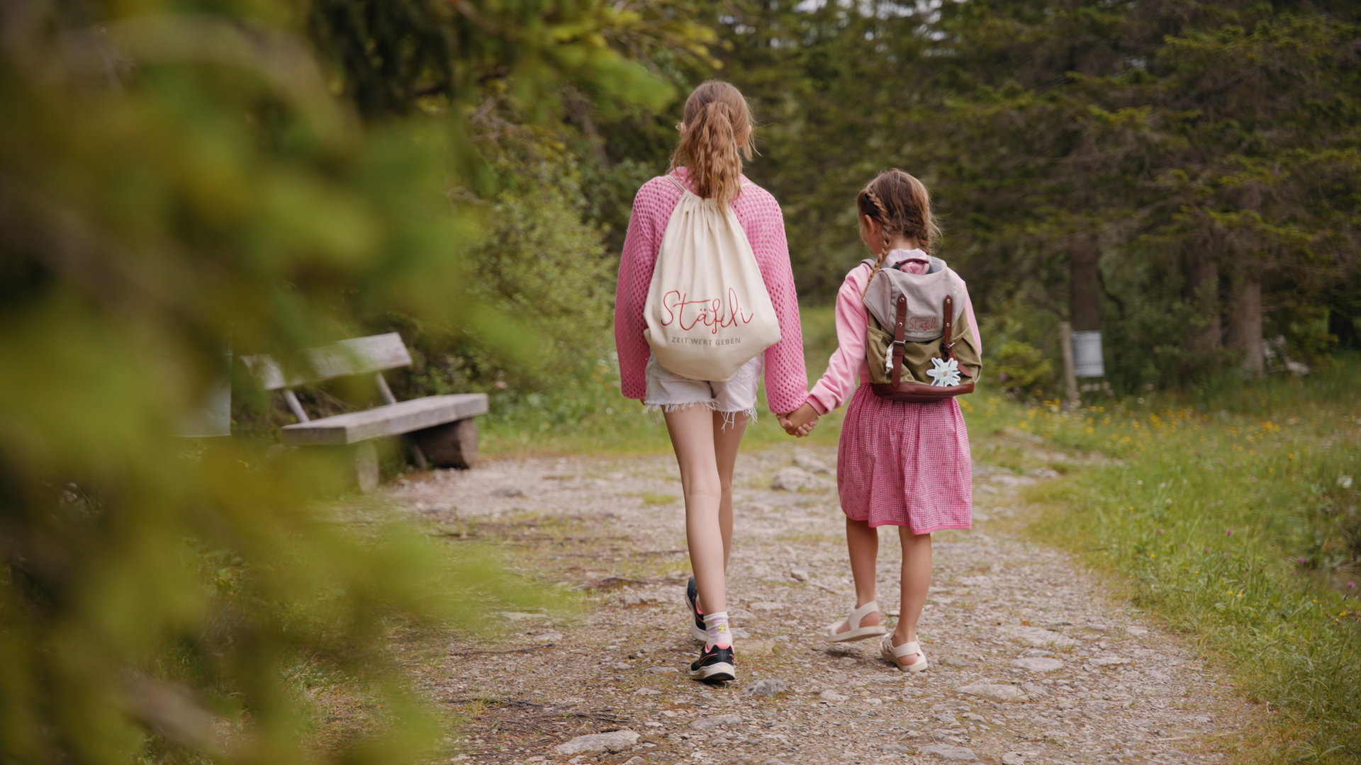 Zwei Mädchen gehen Hand in Hand auf einem Feldweg .
