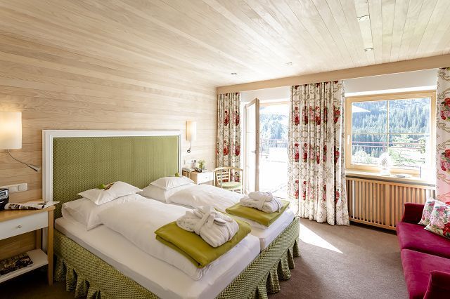 Hotelzimmer mit Doppelbett und Blumnvorhängen