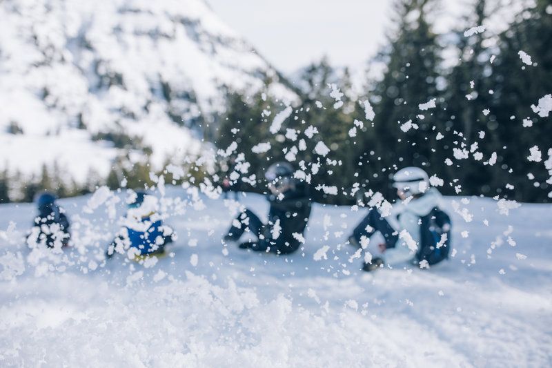 Eine Gruppe von Menschen sitzt im Schnee und wirft Schnee in die Luft .