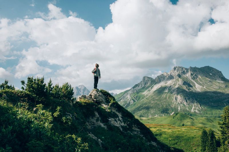 Ein Mann steht auf einem Berggipfel und schaut auf die Berge .