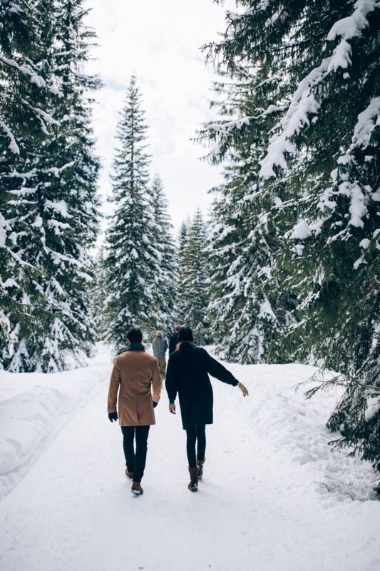 Ein Mann und eine Frau gehen durch einen schneebedeckten Wald .