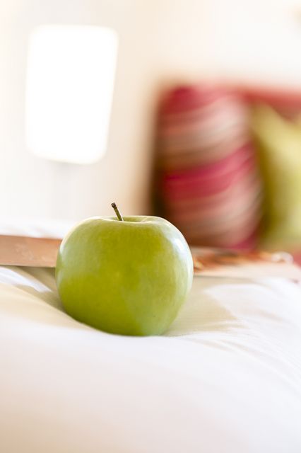 ein grüner Apfel liegt auf einem Bett .