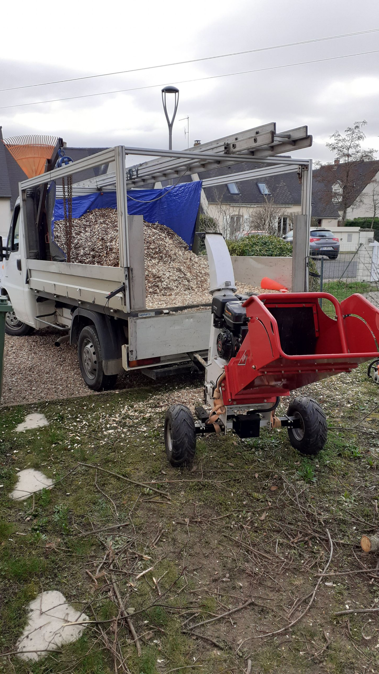 Broyeur de bois à côté d'un camion rempli de copeaux de bois, à l'extérieur.