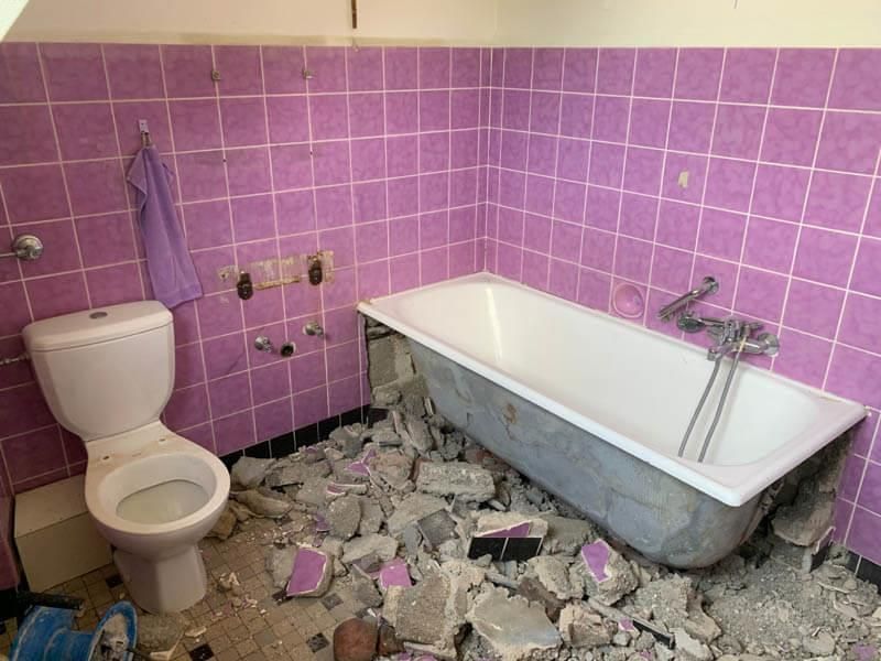 Ein Badezimmer mit rosa Fliesen, einer Toilette und einer Badewanne.