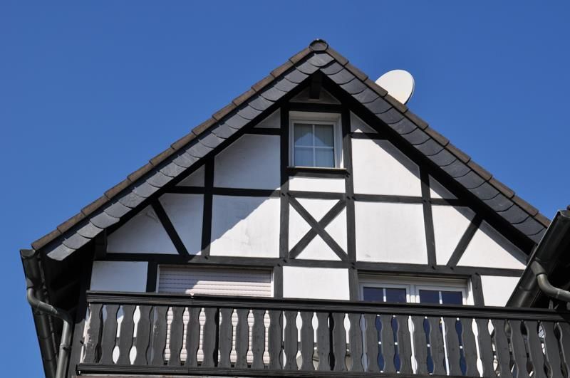 Ein schwarz-weißes Haus mit einem Balkon und einer Satellitenschüssel auf dem Dach