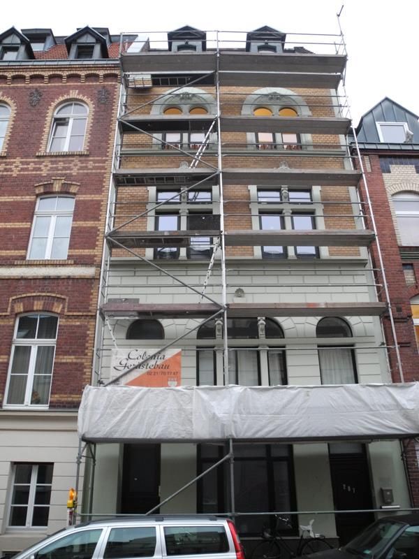 Ein weißer Lieferwagen steht vor einem Gebäude mit Gerüst darauf