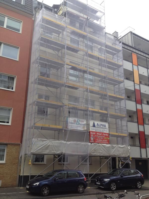 Ein Gebäude mit Gerüsten darauf und davor geparkten Autos