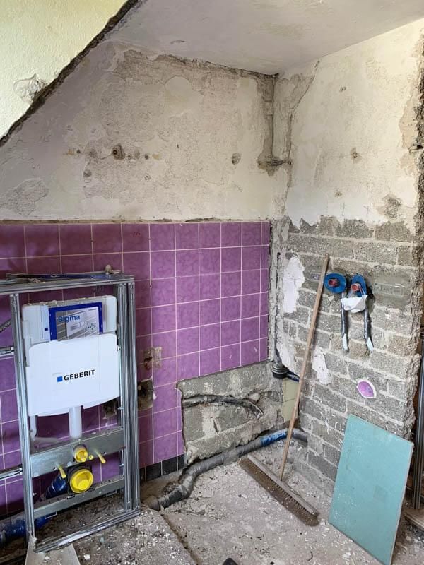 Ein im Bau befindliches Badezimmer mit rosa Fliesen und einer Toilette.