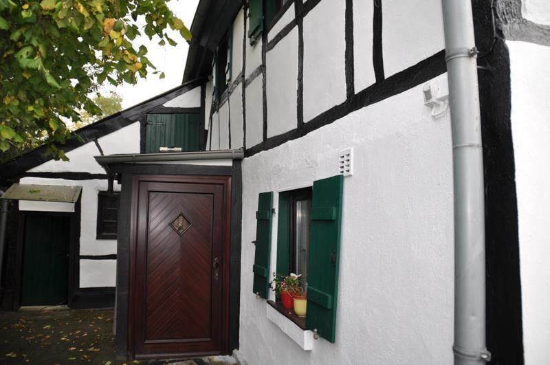 Ein weißes Haus mit einer Holztür und grünen Fensterläden