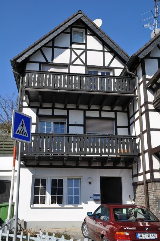 Ein rotes Auto steht vor einem Haus mit Balkon