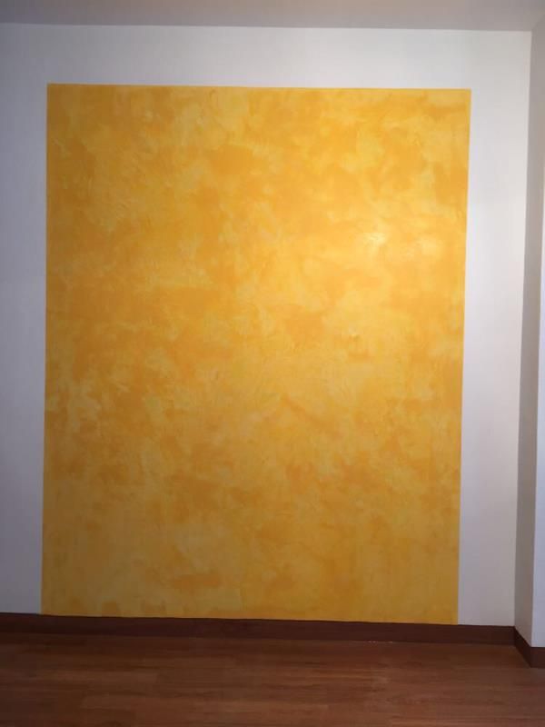 In einem Raum mit Holzboden ist eine gelb gestrichene Wand.