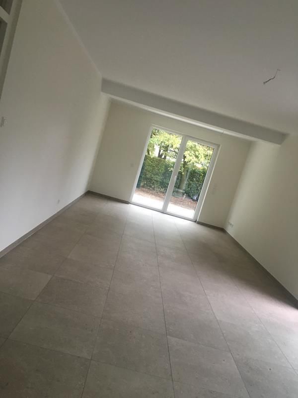 Ein leerer Raum mit einer Glasschiebetür und einem Fenster.