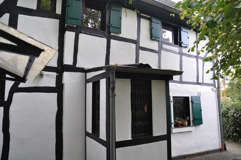 Ein weißes Haus mit schwarzen Verzierungen und grünen Fensterläden