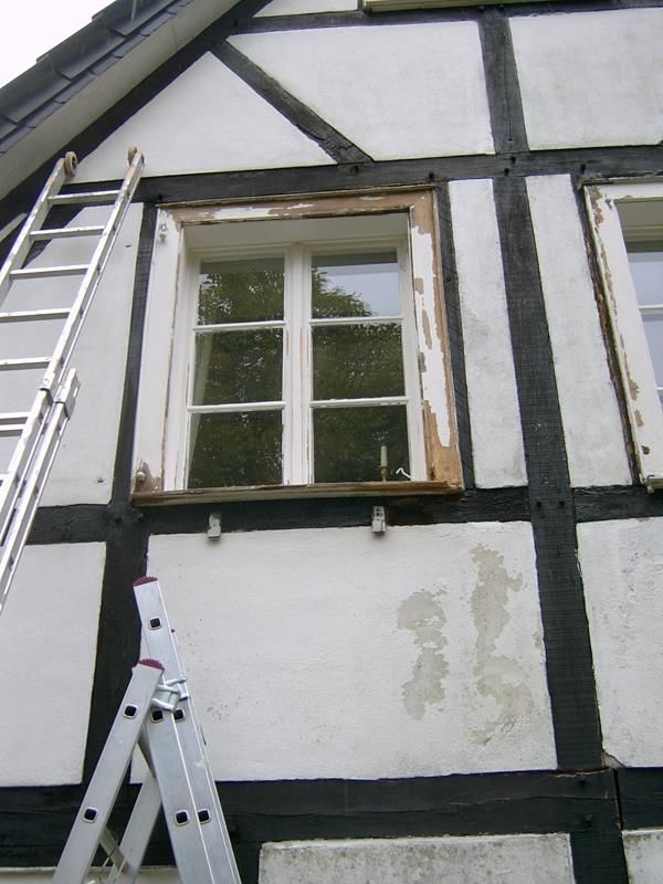 Eine Leiter steht an der Seite eines Gebäudes neben einem Fenster