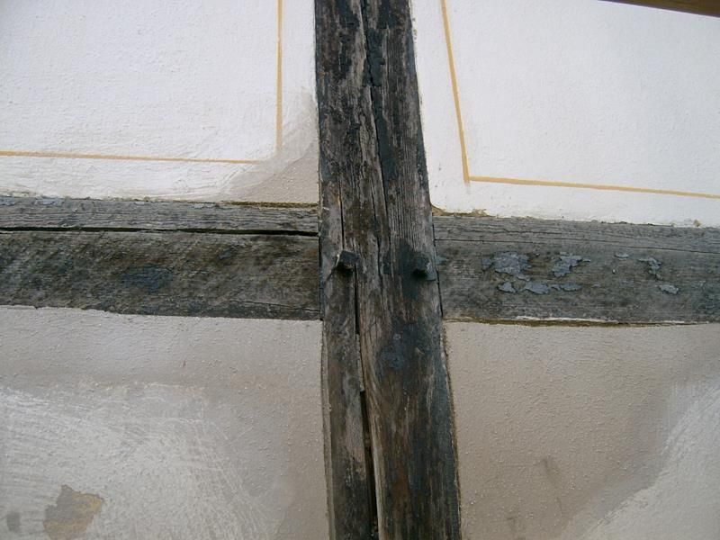 Eine Nahaufnahme von einem Holzkreuz an einer weißen Wand