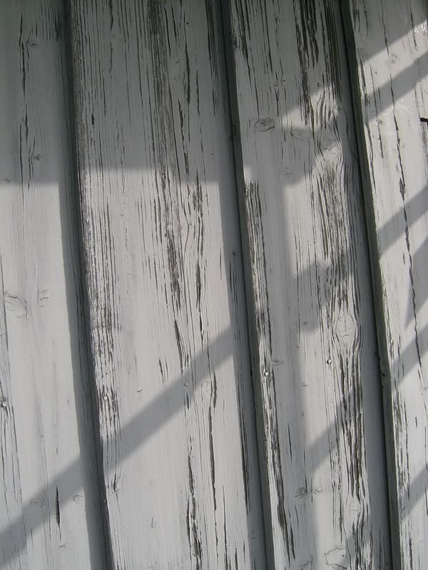 Eine Nahaufnahme einer weißen Holzwand mit einem Schatten darauf