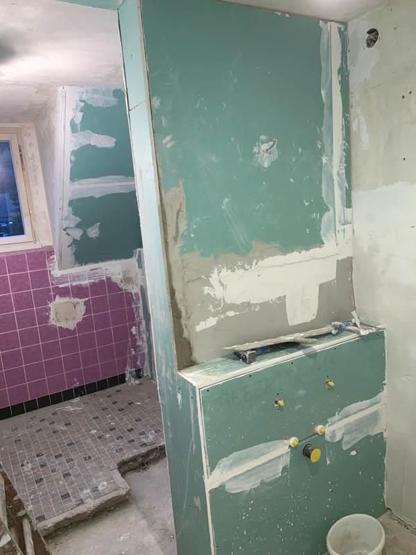 Ein im Bau befindliches Badezimmer mit violetten Fliesen und grünen Wänden